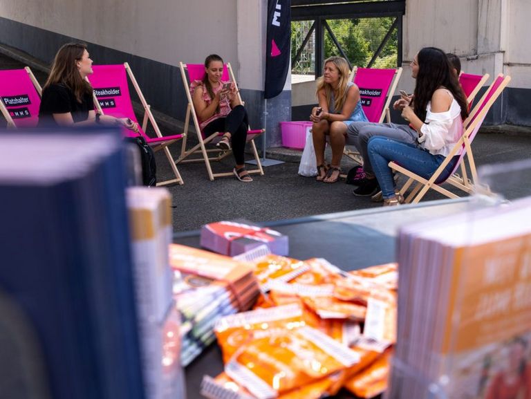 Kollegen sitzen in Klappstühlen auf dem Parkdeck
