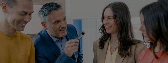 gute_gruende_telekom_mms Zwei Mitarbeiterinnen lächeln einen Kollegen an