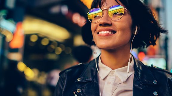 Foto von einer Frau lächelnd mit Sonnenbrille und Kopfhörern