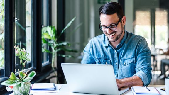 Mann lächelnd mit einem Blick auf seinen Laptop