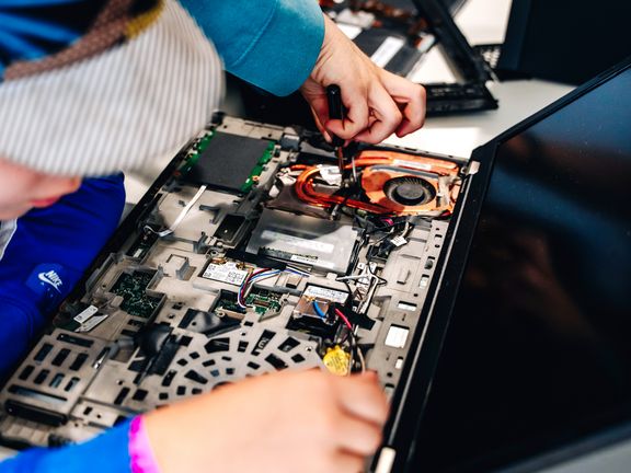 Ein Kind schaut in einen aufgeschraubten Laptop