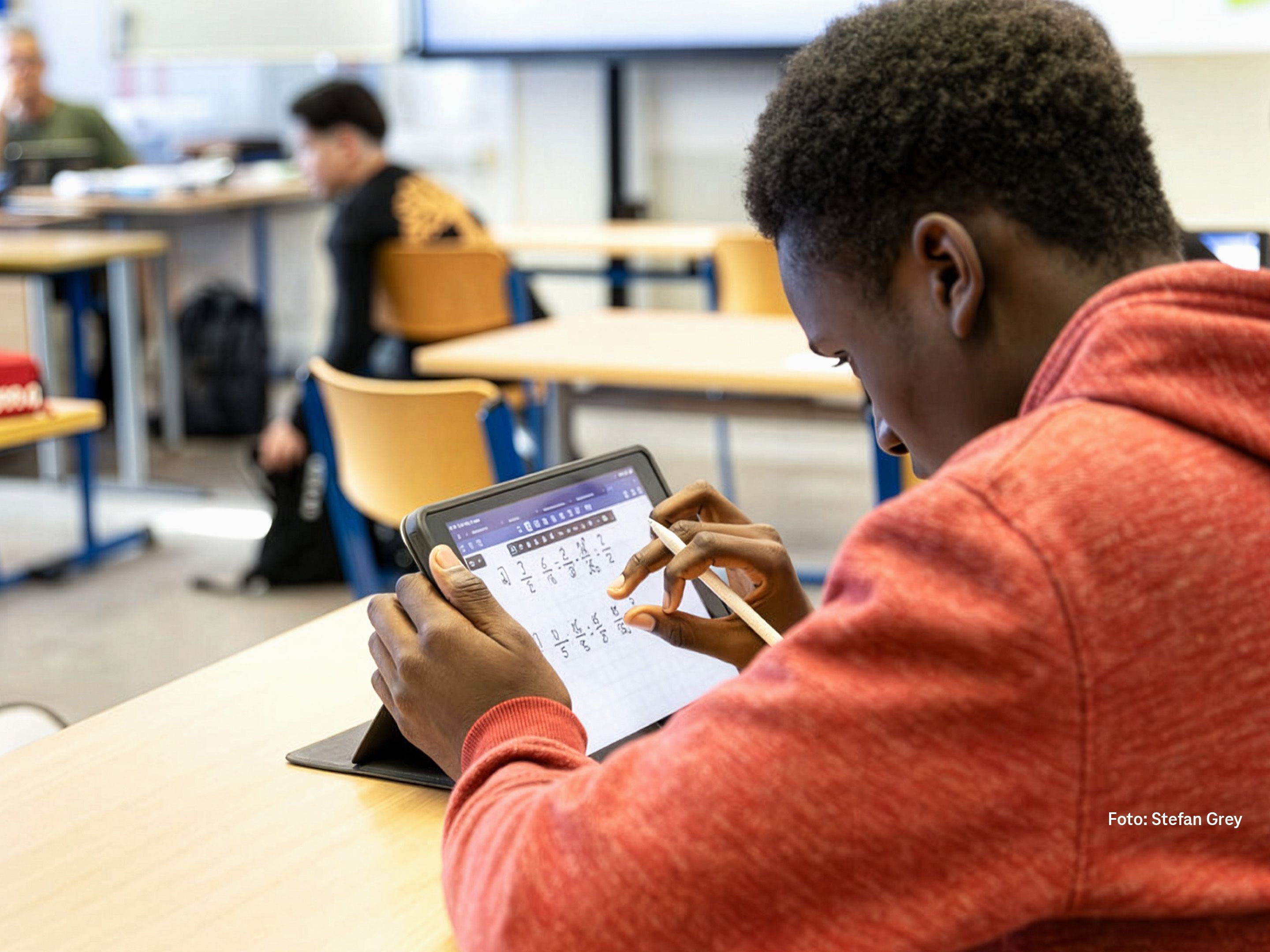 Bild von einem Jungen mit Tablet im Klassenraum