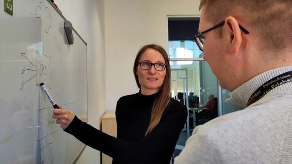 Cloud Engineer Katharina vor einem Whiteboard zusammen mit einem Kollegen
