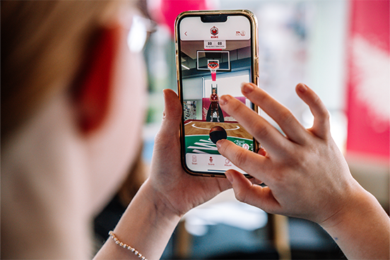 Ein Mädchen hält ihr Handy in der Hand mit der FCBB-Basketball-App