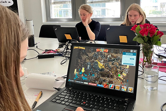Bild zeigt Schülerinnen an Laptops. Auf dem Laptop-Bildschirm sieht man ein Onlinespiel.